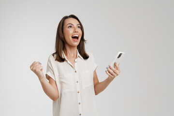 Young woman making winner gesture and using cellphone