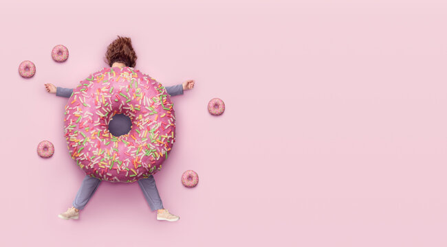 Girl with  donut. Fast food concept, overweight. Minimal pink background with copy space