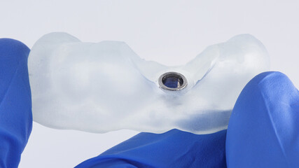 Dental Surgeon holds a special Dental template to install one implant on a white background