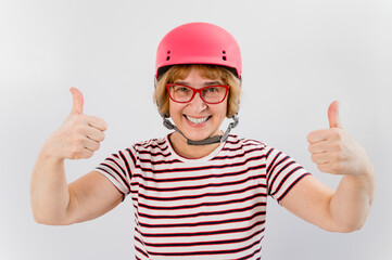 Elderly woman in ski helmet showing thumb up on white background.