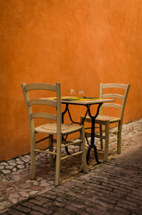 Il tavolino di un ristorante apparecchiato per due in un vicolo arancione a Trevi in Umbria