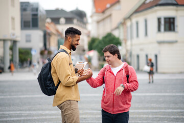Young man with Down syndrome and his mentoring friend meeting and greeting outdoors in town