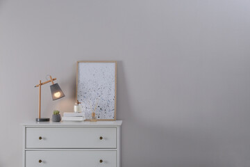 White chest of drawers, lamp and decor in room, space for text. Interior design