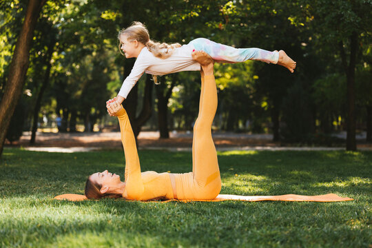 Happy mother lifting daughter on legs in park