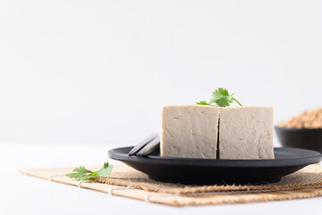 Sliced fresh tofu on black plate with white background, Vegan Food ingredients in Asian food