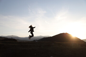 happy woman jumping into the air at sunset.