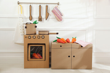 Toy cardboard kitchen with stove and utensils at home
