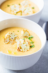 Vegetarian cream cheese soup with cauliflower in white bowl. Healthy vegan food concept.