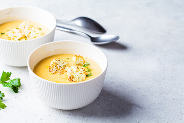 Vegetarian cream cheese soup with cauliflower in white bowl. Healthy vegan food concept.