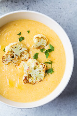 Vegetarian cream cheese soup with cauliflower in white bowl. Healthy vegan food concept.