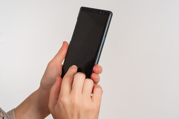 Phone in hand. Woman hands off by phone. Smartphone for application demonstration. Place for application on cellphone screen. Cellphone in human hands on light background. Black display phone