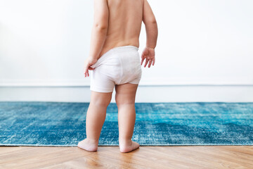 Baby boy pulling on his diapers - obrazy, fototapety, plakaty