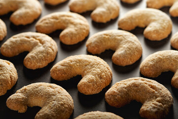 Crescent shaped Christmas cookies (vanilla crescents) on black background.