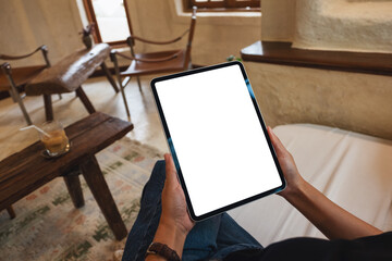 Mockup image of a woman holding digital tablet with blank white desktop screen in cafe