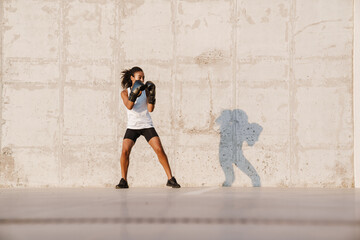 Fototapeta na wymiar Black sportswoman boxing while working out on parking