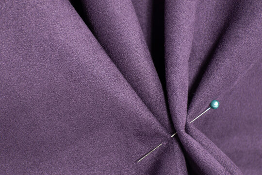 Draped suede. Purple suede fabric. Sewing from suede. Needle on fabric