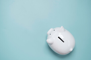 Top view or flat lay of white piggy bank saving on blue background and copy space for deposit and...