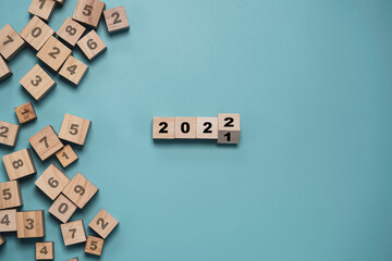 Flipping of wooden cube block for change 2021 to 2022 with other number on blocks on blue...