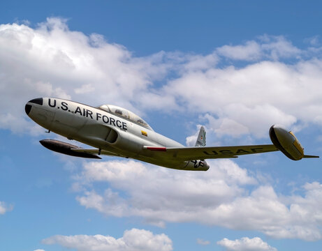 Composite shot of a Lockheed T-33 Shooting Star fighter military jet flying in a blue cloudy sky