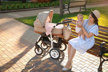 Happy mother with baby sitting on bench in park