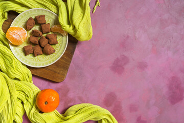 Top view of healthy vegan truffle sweets on a green plate with mandarin orange and yellow green table cloth with copy space