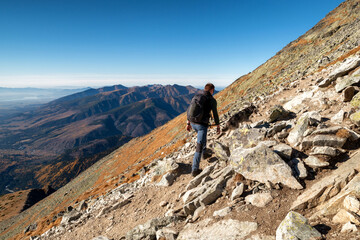 Hiker and dog walking on mountain trail. High Tatras mountains, Slovakia