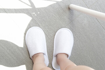 Child in blank white hotel slippers. Towelling disposable spa guest shoes. Top view.