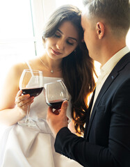 Young newlywed couple drinking wine and smiling at their happiness, romance and tenderness