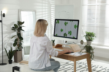 Woman working at table in light room, back view. Home office