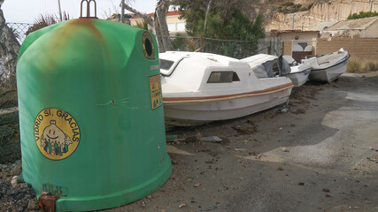 Barcas antiguas para desecho y desguace junto a contenedores