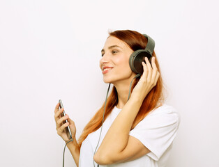 lifestyle and people concept: young ginger woman with headphones listening music.