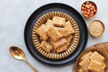  Indian makar sankranti festival food oe sweets. Tilgul in a small brass plate. Tilgul is made out of sesame seeds, peanuts, and jaggery. Til gul chikki or sesame candy. Copy Space.
