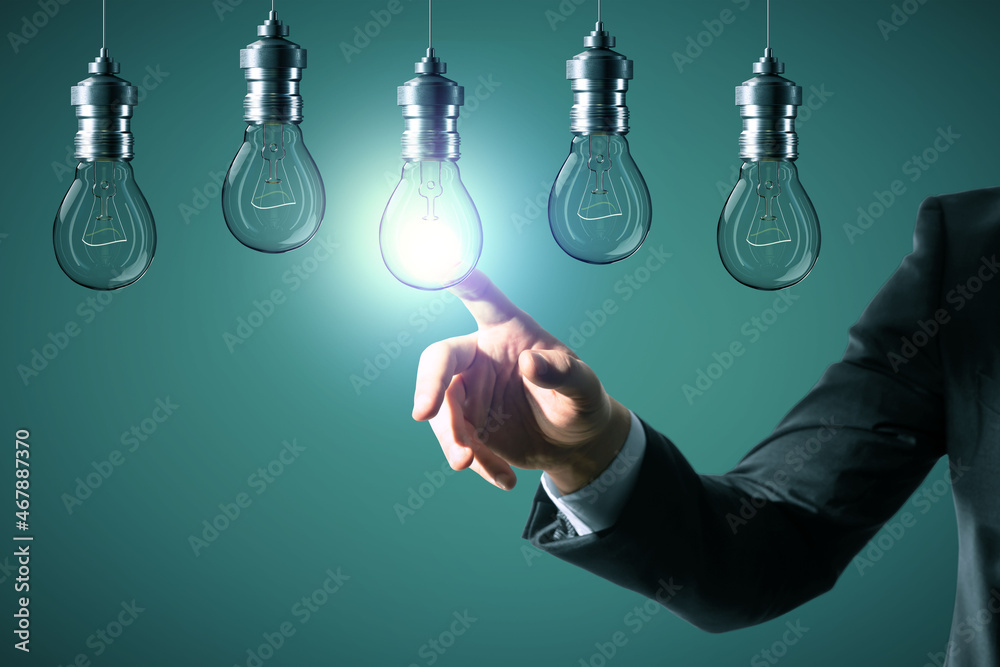Aufkleber close up of businessman hand pointing at abstract glowing row of light bulbs on blue background. ide