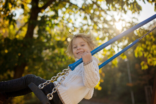 Happy children, playing with pet dog in autumn park on a sunny day