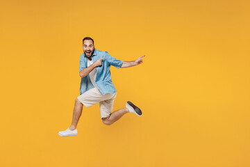 Fototapeta na wymiar Full body young smiling happy caucasian man 20s wearing blue shirt jump high point index finger on workspace area mock up isolated on plain yellow background studio portrait. People lifestyle concept.
