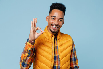 Excited cheerful charismatic overjoyed young black man 20s years old wears yellow waistcoat shirt looking camera showing okay ok gesture isolated on plain pastel light blue background studio portrait.