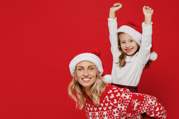 Young cool woman in sweater have fun child baby girl 6-7 years old Mommy little kid daughter give piggyback ride to joyful, sit on back isolated on plain red background. New Year love family concept.