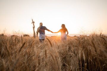Mixed race young adult couple holding hands while walking in field