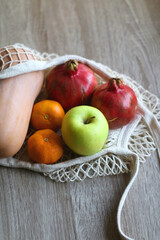 Crochet bag filled with butternut squash, pomegranates, apples and tangeriens. Selective focus.