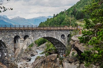 Fototapeta na wymiar Ancient stone arch bridge in the fjords in Norway. Beautiful Scanlinavian landscape