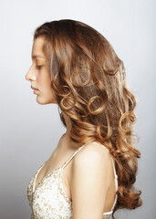 Blonde female model with long and volume shiny wavy hair.