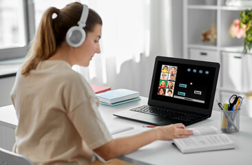 education, school and distant learning concept - female teacher in headphones with laptop computer...