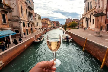 Keuken spatwand met foto Water canals in Venice and white wine glass in hand of happy tourist © radiokafka