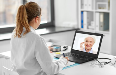Fototapeta na wymiar healthcare, technology and medicine concept - female doctor with laptop computer having video call with patient at hospital