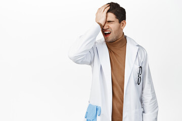 Frustrated doctor facepalm, disappointed in smth, making bad mistake, standing upset against white background, wearing medical uniform