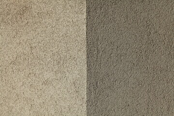 Fototapeta premium Grey and light-gray wall texture, background. Structural plaster, uneven surface. The corner of a wall or building. Abstract two-component background. Rough surface. Textured coating