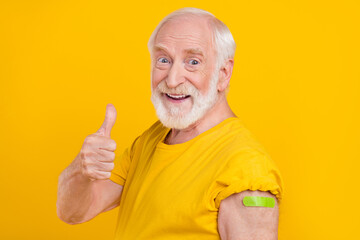 Photo of retired old man approve vaccine effect raise thumb up wear t-shirt isolated yellow color background