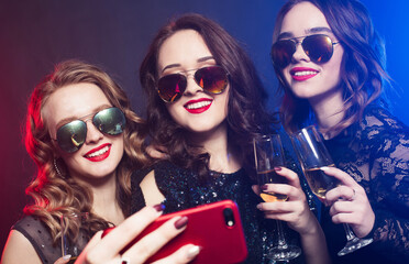 Group of partying girls clinking flutes with sparkling wine and make selfie.