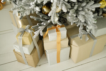 Photo of luxury gift boxes under Christmas tree. New Year home decorations, golden and silver wrapping of Santa presents