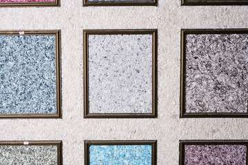Fototapeta premium Samples of colored liquid wallpaper decorative plasters in frames in construction store